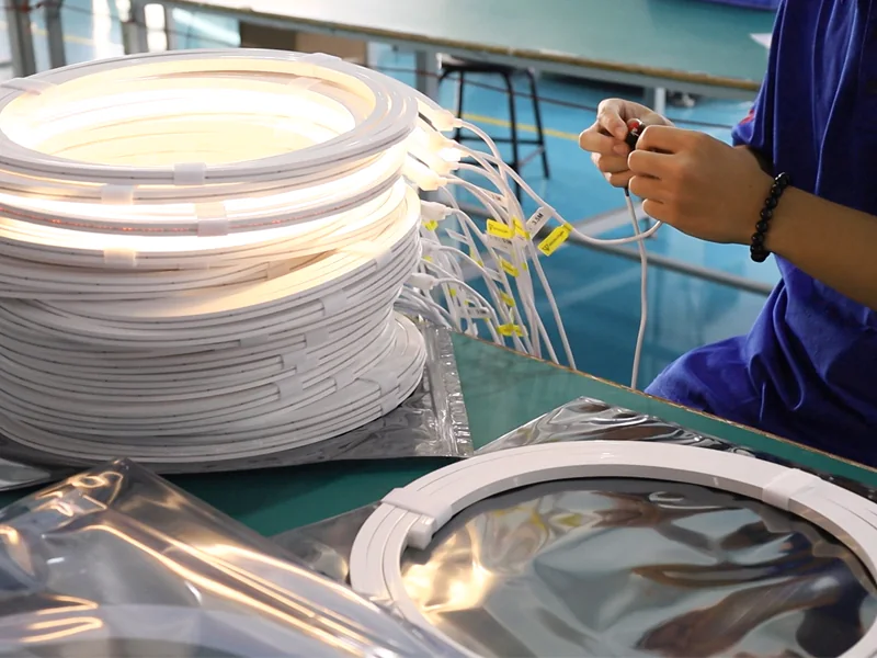 Custom LED Silicone Tube & Profile Manufacturer | AlisterTech Worker checking connections on illuminated coiled lighting assemblies