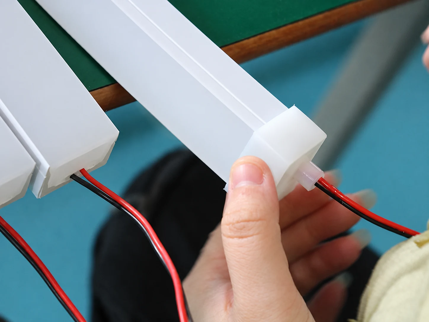 Custom LED Silicone Tube & Profile Manufacturer | AlisterTech Worker checking an end cap and cable connection on a white lighting profile