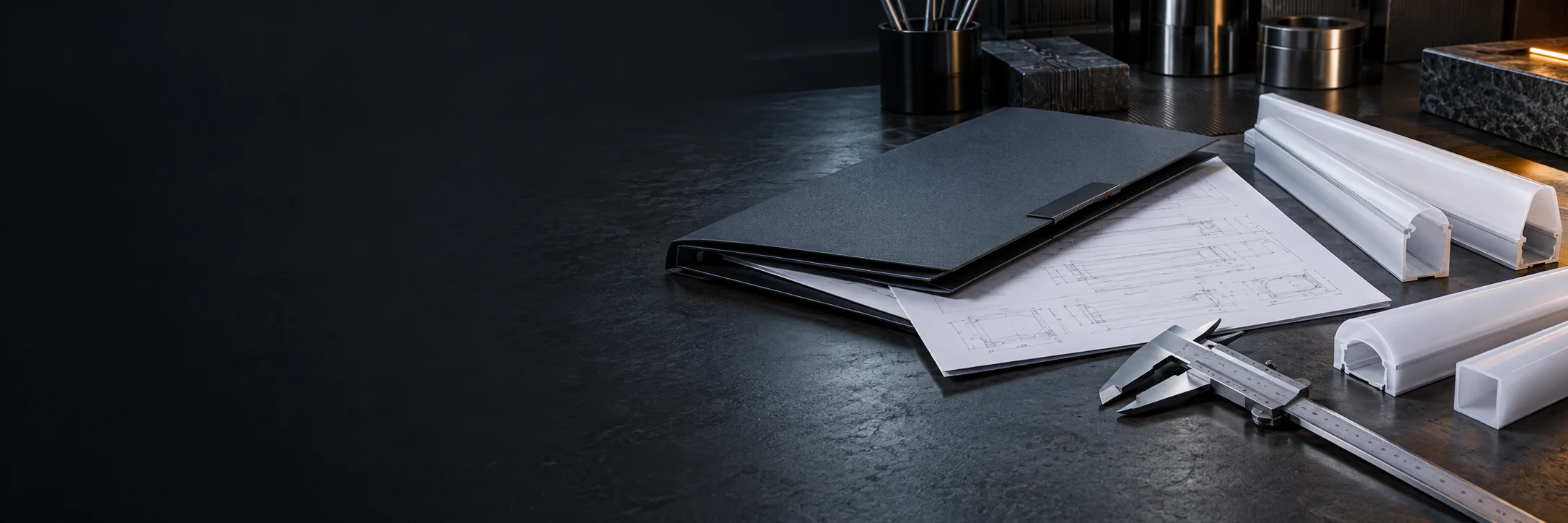 Illustrative engineering documents and silicone lighting profiles on a workbench