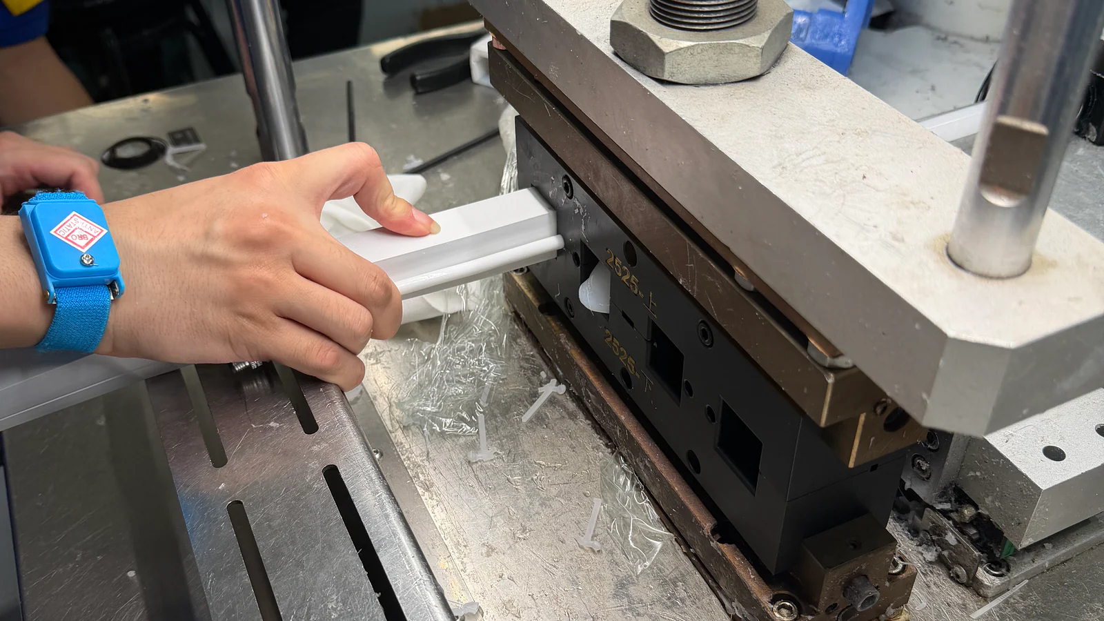 White silicone profile being checked at extrusion tooling during a production trial