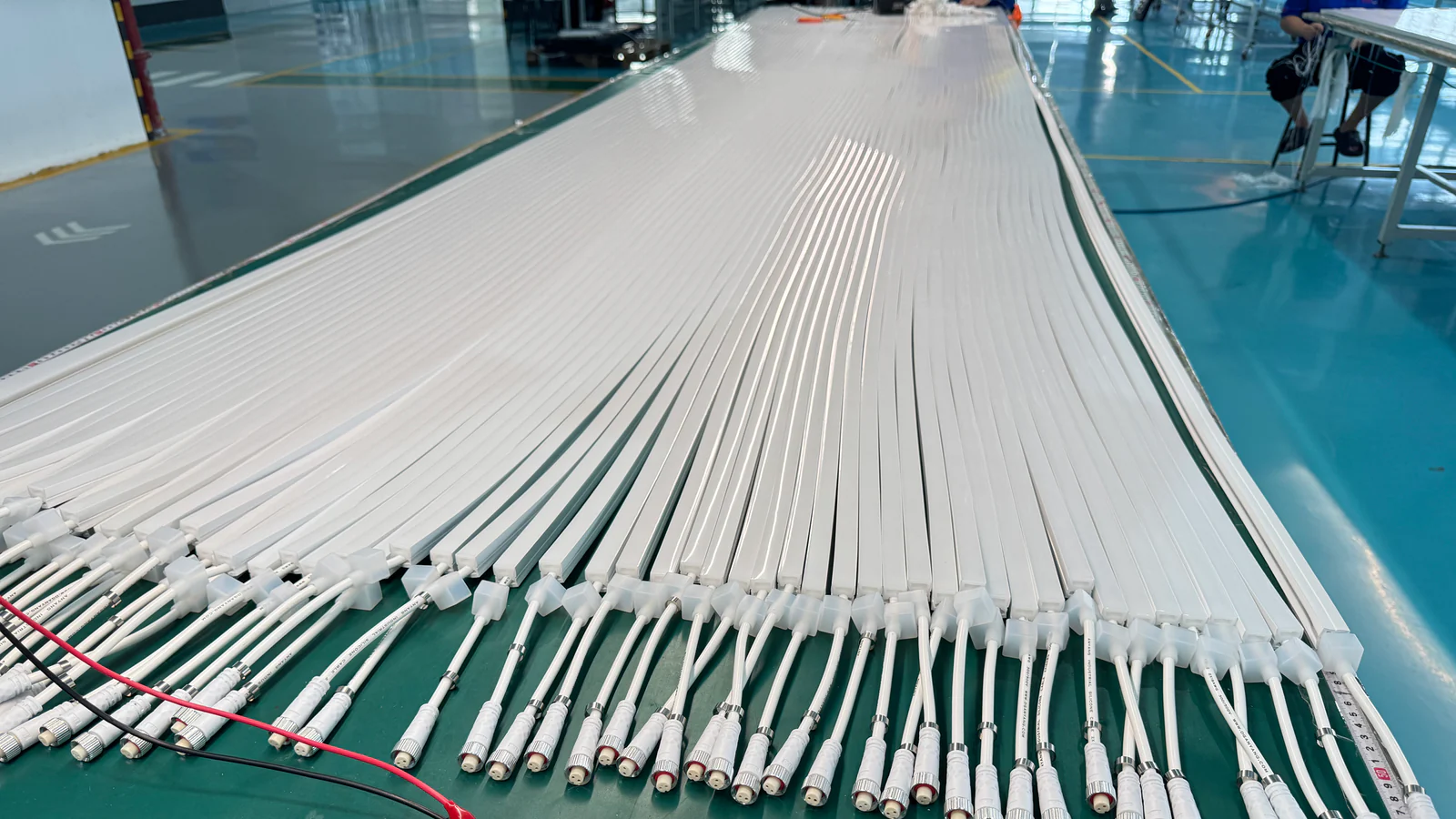 Rows of assembled white linear lighting profiles with cable connectors prepared for review