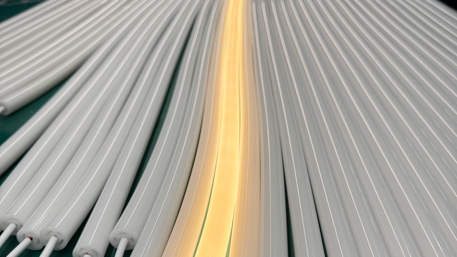 White silicone lighting profiles with one warm-white illuminated sample among unlit profiles