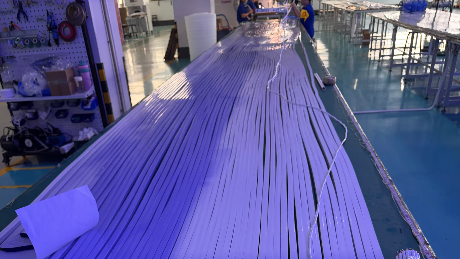 Rows of white lighting profiles arranged on an assembly workbench for review