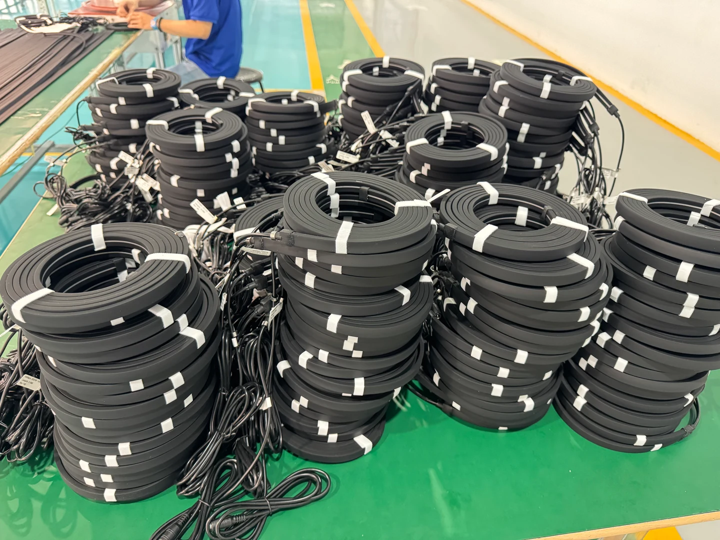 Coiled black lighting profiles with cable ends on a workshop table