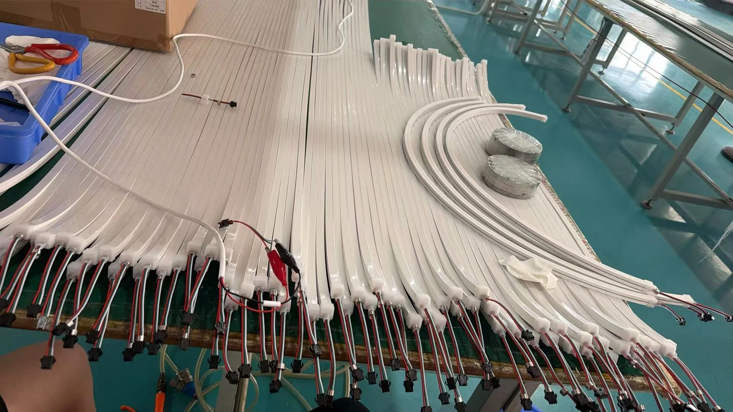White lighting profile segments and cable connections laid out on a workbench